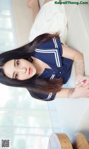 A woman in a black bathing suit sitting on a white couch.