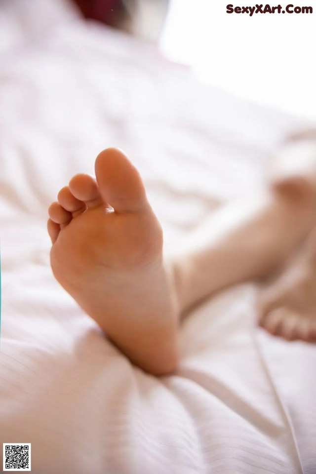 A close up of a person's bare feet on a bed.