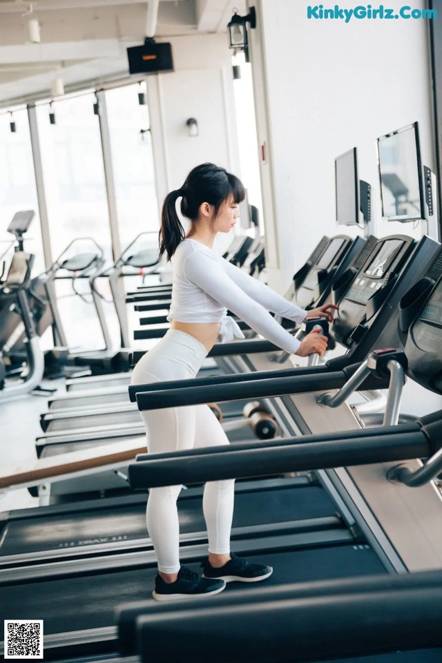 A woman running on a treadmill in a gym.