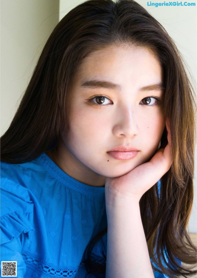 A young woman with long brown hair and a blue shirt.