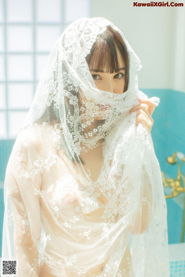 A woman in a white lingerie with a veil over her head.