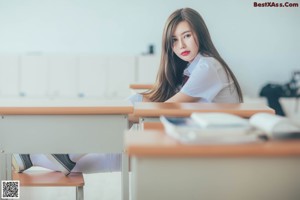 A naked woman sitting on top of a wooden desk.