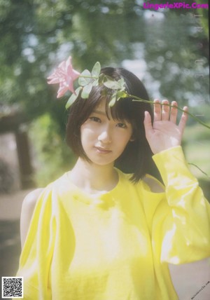 A woman in a yellow top and white skirt standing in the woods.