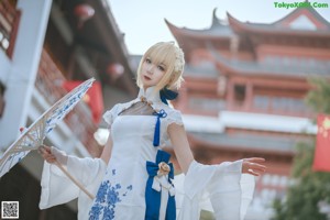 A woman in a white dress holding an umbrella.