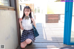 A young woman in a school uniform leaning against a blue door.