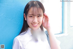 A young woman in a school uniform sitting on a wooden floor.