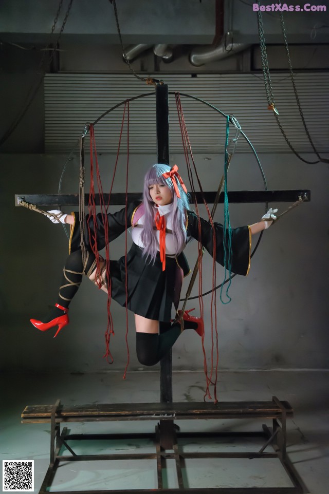 A woman in a black dress and red shoes is suspended on a swing.