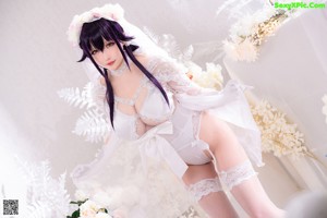 A woman in a white lingerie sitting on the floor.