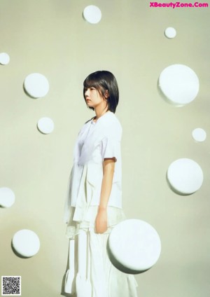 A woman in a white dress standing in front of a mirror.