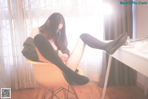 A woman sitting on a yellow chair with her legs crossed.