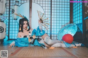 A woman in a blue and white outfit sitting on the floor.