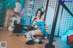 A woman in a blue and white outfit sitting on a chair.