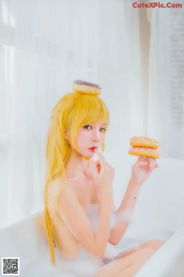 A woman sitting in a bathtub holding a donut.