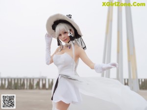 A woman in a white dress and hat sitting on some steps.