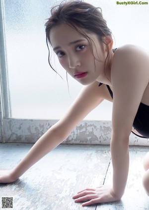 A woman in a black bathing suit sitting on the floor.