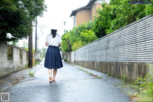 A woman in a white shirt and blue skirt holding an umbrella.