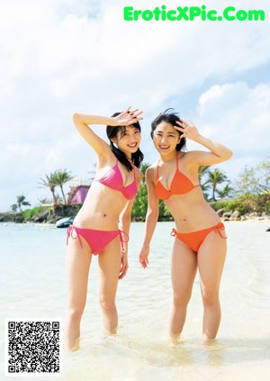 A couple of young women standing next to a swimming pool.