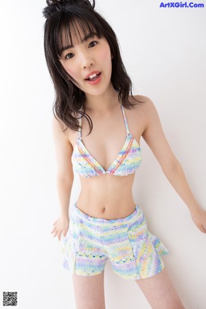 A young woman in a bikini top and shorts posing for a picture.