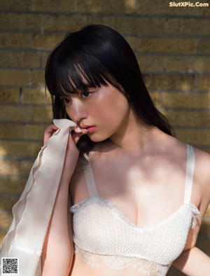 A woman in a white bra sitting on the ground.