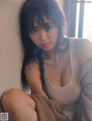 A woman in a brown sweater and pink panties sitting on a couch.
