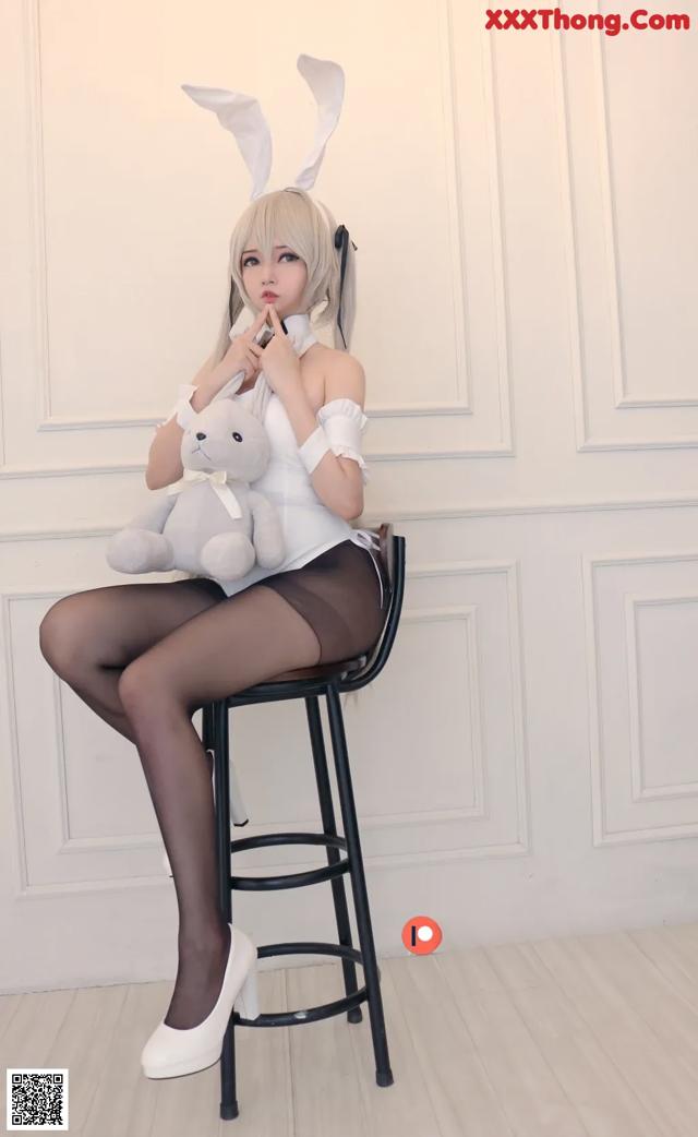 A woman sitting on a stool holding a teddy bear.