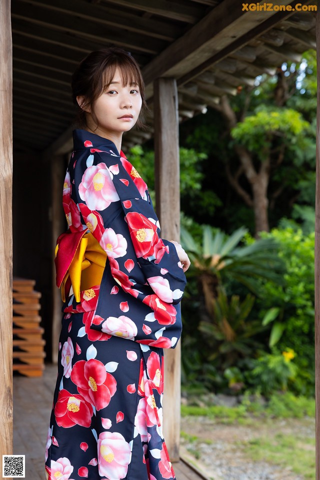 A woman in a kimono standing in front of a wooden structure.