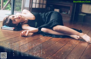 A woman sitting on a wooden deck eating a slice of watermelon.