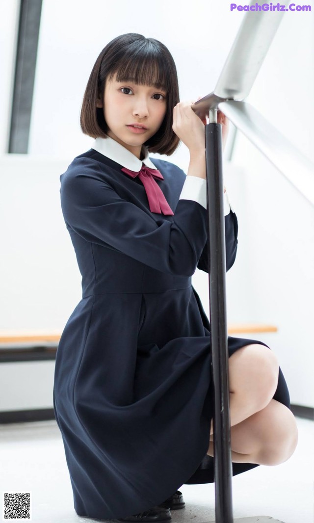 A woman in a school uniform crouching down on the floor.