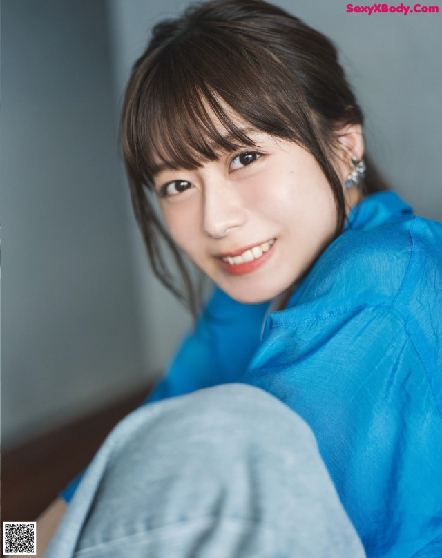 A woman in a blue shirt smiles at the camera.