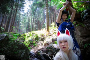 A couple of women laying on top of a moss covered rock.