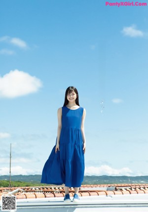 A woman in a blue dress laying on a bed.