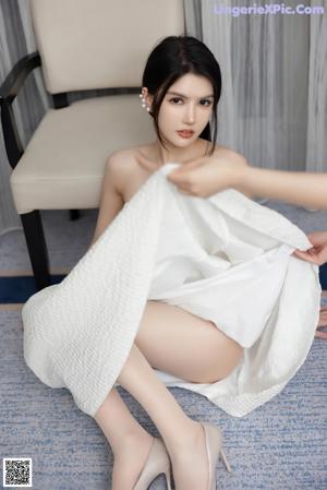 A naked asian woman sitting on a blue couch.