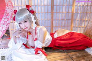 A woman in a white and red dress sitting on a wooden floor.