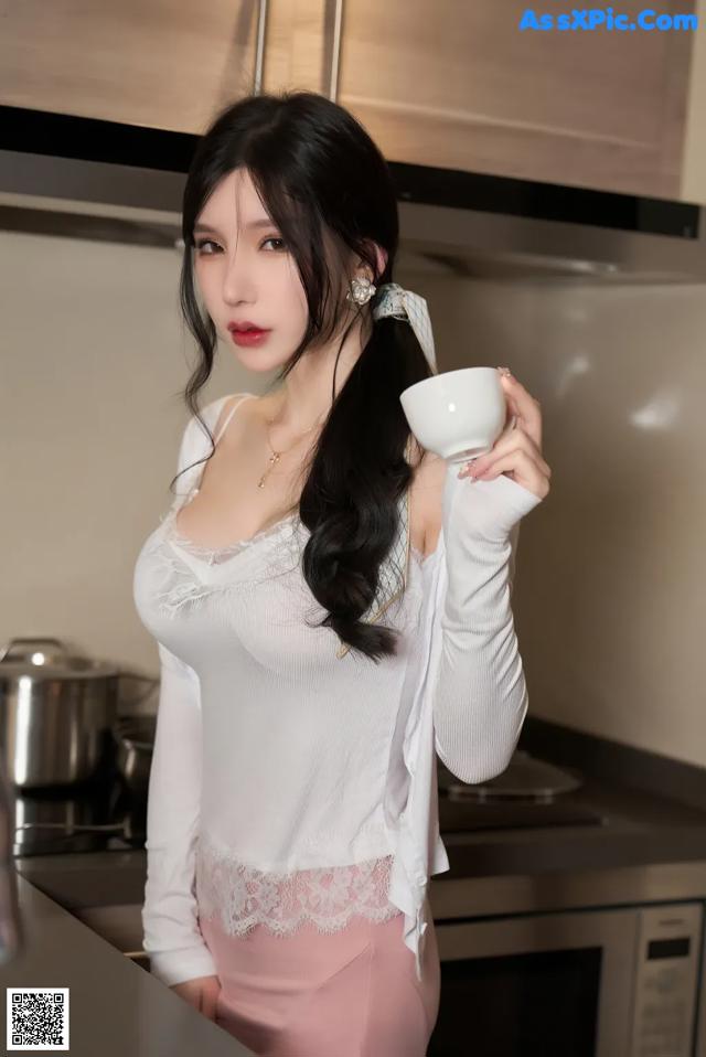 A woman holding a cup of coffee in a kitchen.